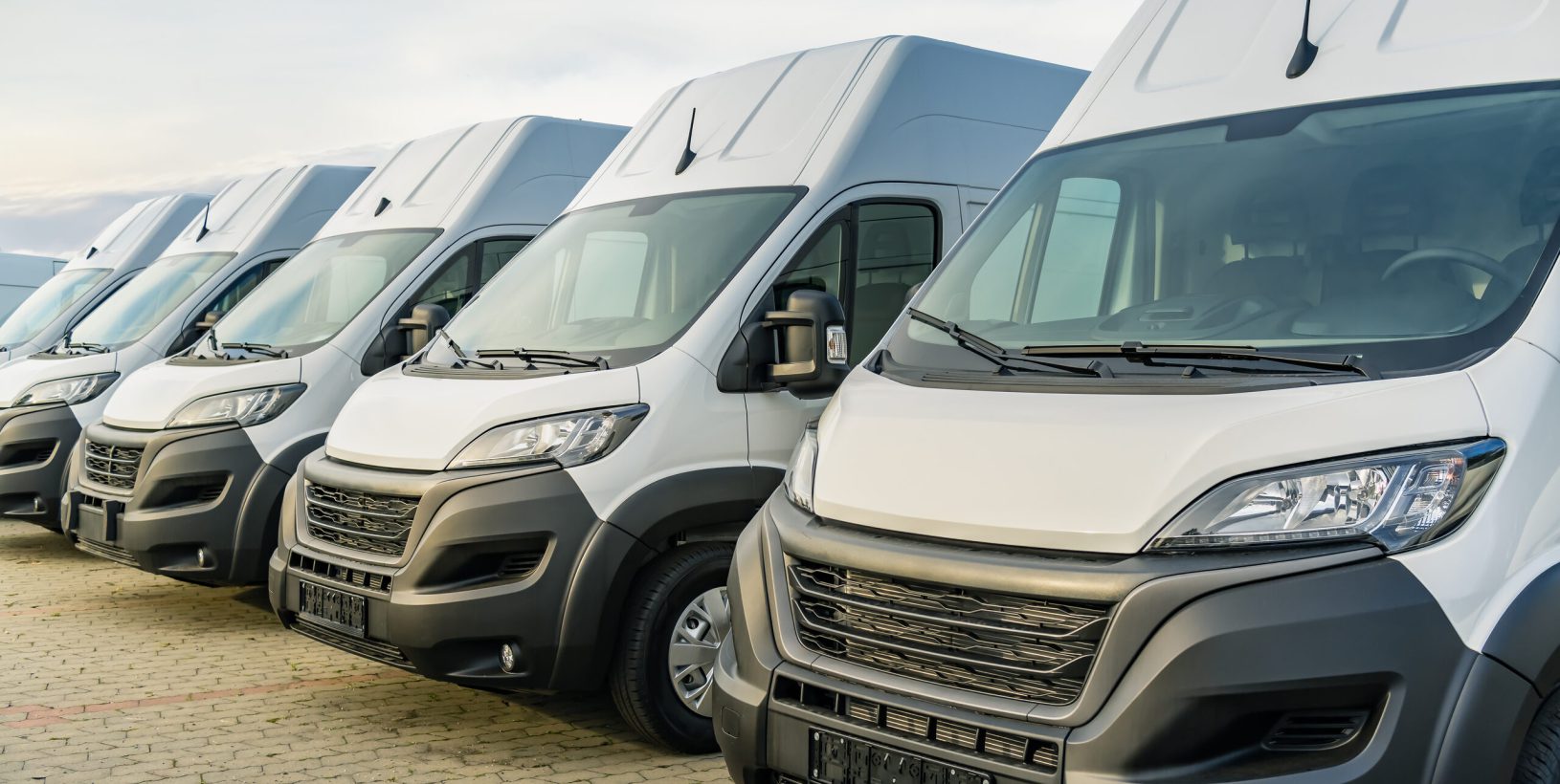 Row of white fleet vans parked together