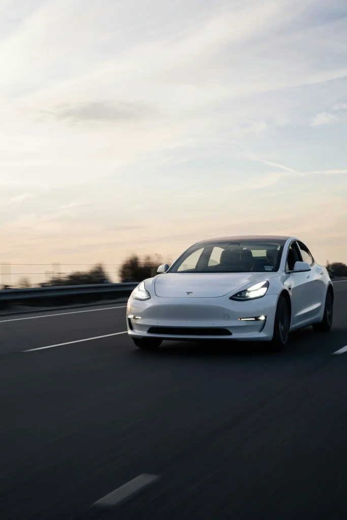 Tesla driving on a road at sunset.