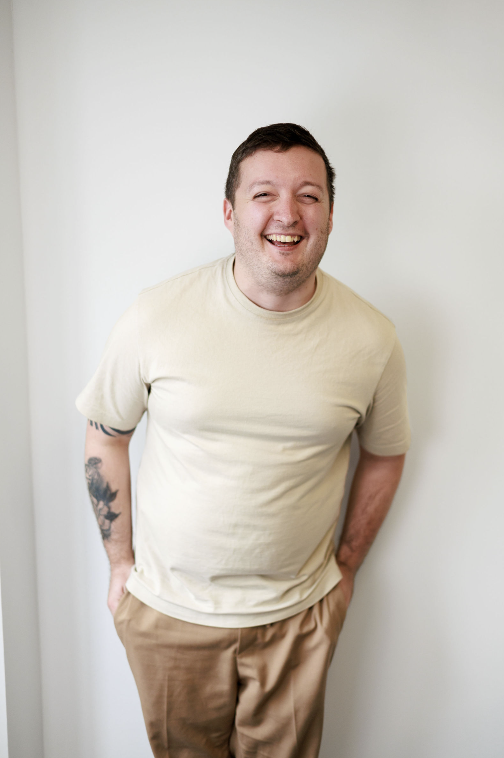 Smiling man standing against a light wall